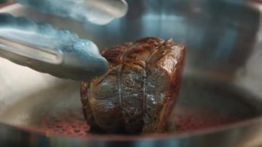 Close-up of a filet mignon being cooked in frying pan