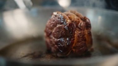Close-up of a filet mignon being cooked in frying pan