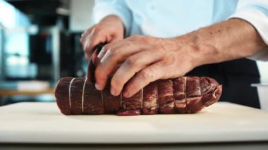 Close-up: The chef cuts the meat of the filet mignon with a knife. The process of preparing food in restaurant.