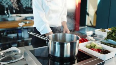 Close-up: The chef adds ingredients to the pot. The process of preparing food in restaurant.