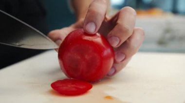Professional restaurant kitchen, close-up: Chef cuts tomatoes with knife