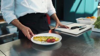 Professional restaurant kitchen, close-up: The chef serves omelette