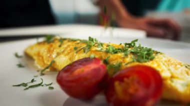 Professional kitchen of the restaurant, close-up: The chef sprinkles the finished omelet with herbs before serving to the guests, customers of restaurant