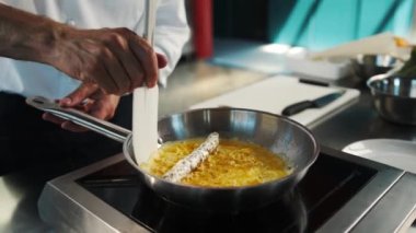 Professional restaurant kitchen, close-up: a man adds sauce to a french omelette while cooking on pan