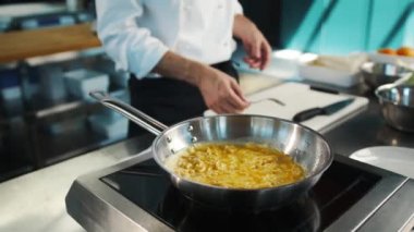 Professional restaurant kitchen, close-up: the process of cooking an omelette in frying pan