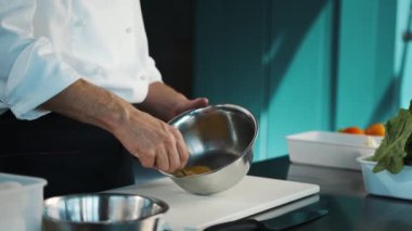 Professional restaurant kitchen: Chef whisking eggs in a bowl