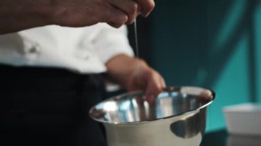 Professional restaurant kitchen: a chef breaks eggs in a bowl