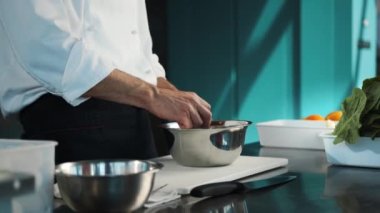 Professional restaurant kitchen: a chef breaks eggs in a bowl