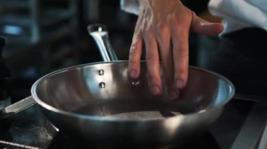 Professional restaurant kitchen: the chef checks the temperature of the frying pan
