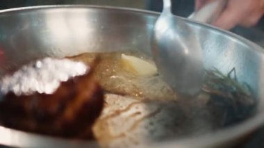 Close-up of filet mignon with thyme being cooked in frying pan
