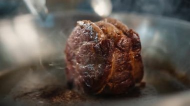 Close-up of a filet mignon being cooked in frying pan