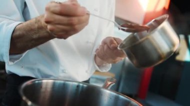 The chef makes sauce in a saucepan in a professional restaurant kitchen. The process of food preparation.