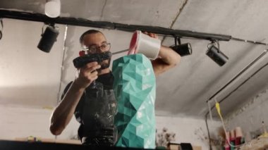 Male sculptor handyman creates handmade vase. The paint is poured into the object.