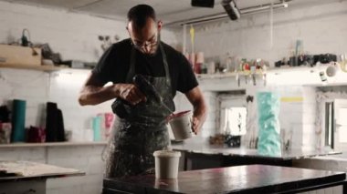 A man works with paint in his trowel. Mixes paint with polymer.