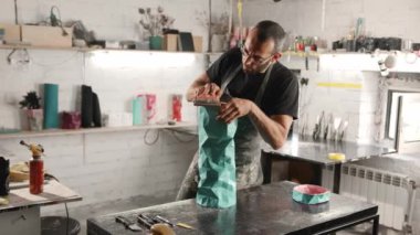 A male craftsman creates decorative product with his own hands. Handmade, workshop. Creative chaos.