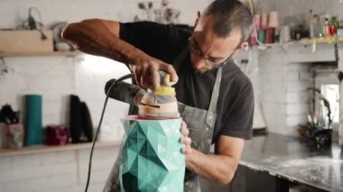 A male craftsman creates decorative product with his own hands. Handmade, workshop. Creative chaos.