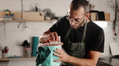 A male craftsman creates decorative product with his own hands. Handmade, workshop. Creative chaos.