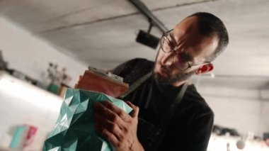 A male craftsman creates decorative product with his own hands. Handmade, workshop. Creative chaos.