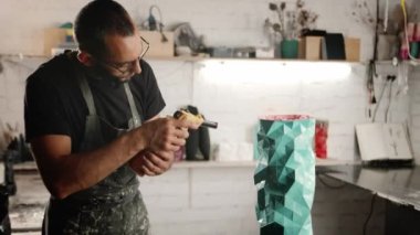 Male craftsman burns his product with gas burner in the workshop