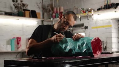 Close-up: male artisan, sculptor works, product in workshop