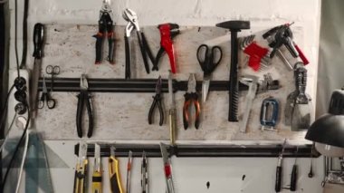 Workshop: wall with hanging tools. Pliers, hammer, scissors, spatula, blades
