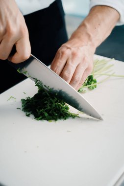 Close-up of a chef finely chopping herbs in a professional kitchen