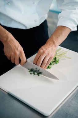 Close-up of a chef finely chopping herbs in a professional kitchen