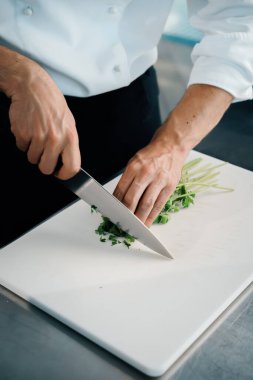 Close-up of a chef finely chopping herbs in a professional kitchen