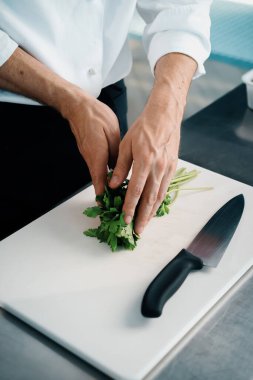 Close-up of a chef finely chopping herbs in a professional kitchen