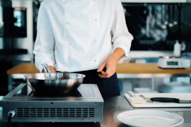 Close-up of a chef preparing a french omelette on a frying pan in professional kitchen