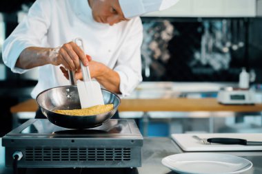 Close-up of a chef preparing a french omelette on a frying pan in professional kitchen