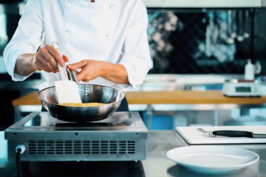 Close-up of a chef preparing a french omelette on a frying pan in professional kitchen