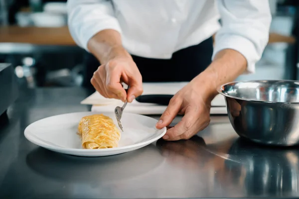 Close-up of a chef preparing a french omelette on a frying pan in professional kitchen
