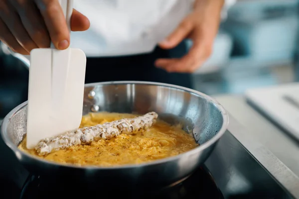 Close-up of a chef preparing a french omelette on a frying pan in professional kitchen