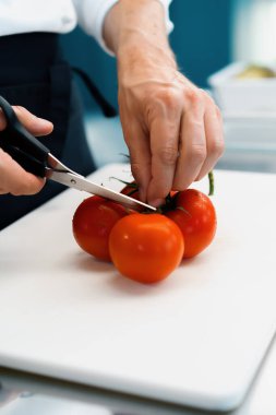Close-up of chef slicing tomato in a professional restaurant kitchen