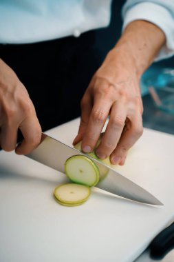 Close-up of chef slicing zucchini in a professional restaurant kitchen