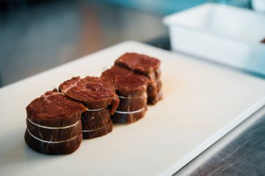 Professional restaurant kitchen, close-up: Chef cut meat for the filet mignon before cooking