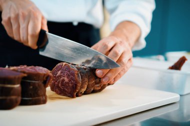 Professional restaurant kitchen, close-up: Chef cut meat for the filet mignon before cooking