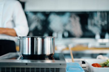 Wide angle: professional cuisine in restaurant. Stove, saucepan, vegetables
