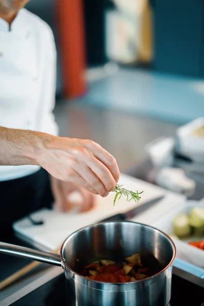 Professional restaurant kitchen, close-up: the chef throws greens into pan