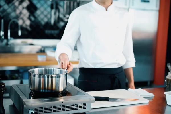 Professional kitchen of the restaurant, close-up: steam from the pot, process of preparing the sauce