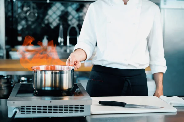 Professional kitchen of the restaurant, close-up: fire from the pot, process of preparing the sauce
