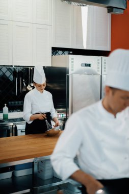 Professional restaurant kitchen: female chef cooker mixes the ingredients