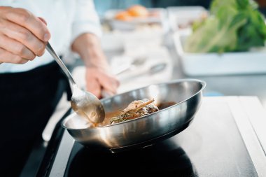 Professional restaurant kitchen, close-up: male chef preparing filet mignon on frying pan