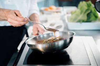 Professional restaurant kitchen, close-up: male chef preparing filet mignon on frying pan