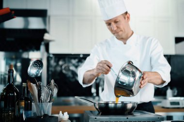 Professional kitchen of a restaurant, close-up: a male chef prepares french omelette in a frying pan