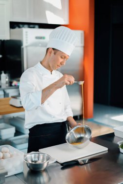 Restaurant professional kitchen: chef prepares delicious dish, beats eggs in a bowl