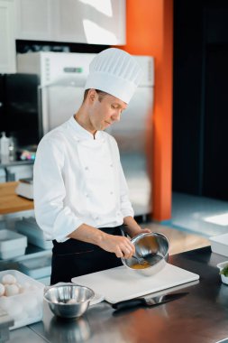 Restaurant professional kitchen: chef prepares delicious dish, beats eggs in a bowl