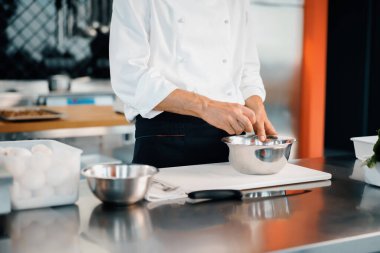 Restaurant professional kitchen: chef prepares delicious dish, beats eggs in a bowl