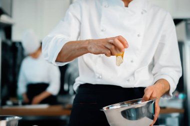 Restaurant professional kitchen: chef prepares delicious dish, beats eggs in a bowl
